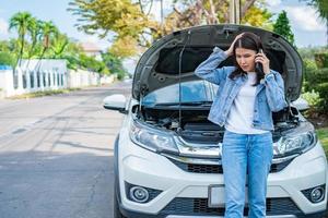 boze aziatische vrouw en het gebruik van een mobiele telefoon die om hulp vraagt na een autopech op straat. concept van voertuigmotorprobleem of ongeval en noodhulp van professionele monteur foto