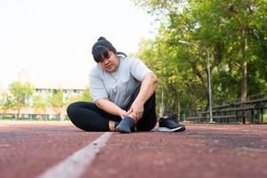 Aziatisch te zwaar vrouw een nieuw loper pijn enkel gedurende rennen, atleet loper opleiding ongeluk. sport rennen enkel verstuikt verstuiking oorzaak blessure. gewicht verlies, training, sport, Gezondheid zorg concepten foto