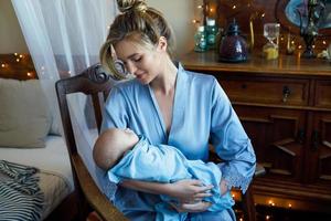 jong mooi moeder met haar schattig weinig baby verpakt in de blauw kleding foto