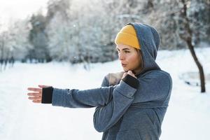 jong atletisch vrouw opwarming omhoog voordat haar winter training foto