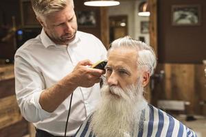 kapper maken elegant kapsel voor een knap oud Mens foto