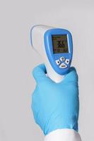 dokter is Holding een digitaal infrarood thermometer foto