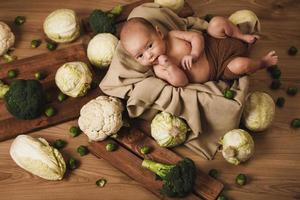 weinig baby is aan het liegen in de doos met een veel van verschillend kool foto