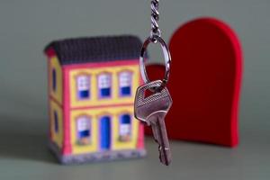 huis symbool met metaal sleutel en eigendom miniatuur, symboliseert huis eigendom foto