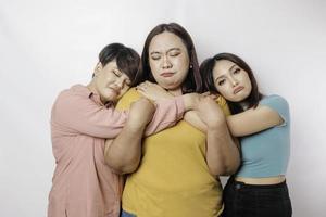 een portret van drie vrienden op zoek verdrietig huilen afgeveegd haar tranen en knuffel elk ander, geïsoleerd wit achtergrond foto