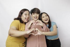 drie Aziatisch Dames voelen gelukkig en een romantisch vormen hart gebaar drukt uit inschrijving gevoelens, dichtbij vriendschap concept. foto