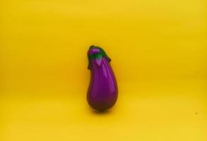 plastic speelgoed- in de het formulier van aubergine of met de Latijns naam solanum melongena Aan een geel achtergrond geïsoleerd foto