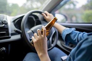 hand- Holding alcoholisch fles terwijl het rijden, detailopname. foto