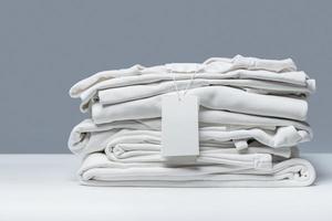 stack van nieuw wit kleren met een blanco kledingstuk label foto