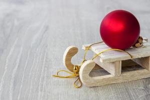 een houten slee met een rood Kerstmis bal Aan het. voorbereidingen treffen voor de nieuw jaar. foto