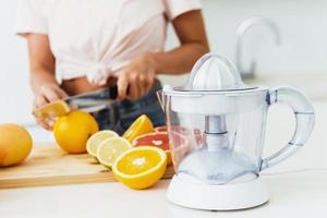 sapcentrifuge en jong vrouw is snijdend citrus fruit voor eigengemaakt vers sap foto