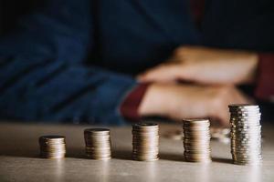 bedrijf vrouw hand- berekenen haar geld in de einde van maand met munt, rekenmachine en kalender Aan houten tafel foto