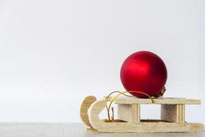 een houten slee met een rood Kerstmis bal Aan het. voorbereidingen treffen voor de nieuw jaar. foto