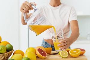 vrouw gieten vers geperst eigengemaakt oranje sap in de glas foto