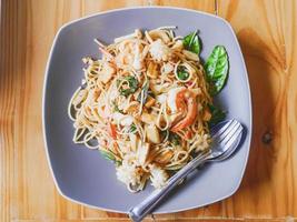 pittig zeevruchten spaghetti in grijs schotel Aan houten tafel foto