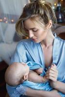 jong mooi moeder met haar schattig weinig baby verpakt in de blauw kleding foto