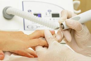 manicure meester werk. dichtbij omhoog van vrouw nagels en handen met een speciaal machine hulpmiddel. foto