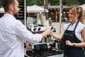 mooi vrouw barista verkoop koffie naar de klant foto