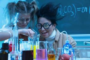 leraar en weinig meisje gedurende chemie les menging Chemicaliën in een laboratorium foto