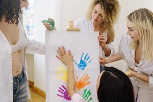 groep van Dames verf Aan canvas en drinken wit wijn gedurende partij Bij huis foto