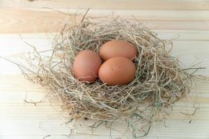 vers bruin kip eieren in hooi nest Aan blauw houten achtergrond. concept van biologisch eieren, vrij ruimte voor tekst of andere elementen foto