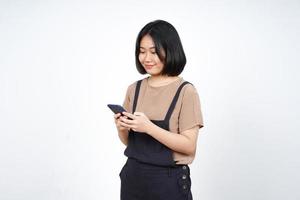 gebruik makend van smartphone en glimlachen van mooi Aziatisch vrouw geïsoleerd Aan wit achtergrond foto