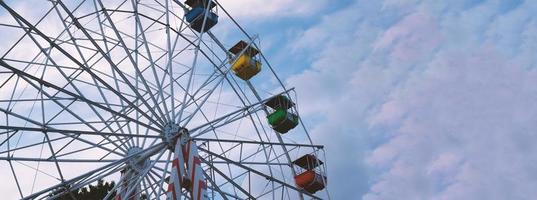 kleurrijk ferris wielen in de amusement park Aan een achtergrond van blauw lucht met wolken. afgezwakt afbeelding. bodem visie foto