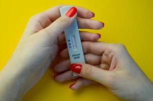 test voor coronavirus Aan een geel achtergrond. medisch analyse. meisje met helder rood manicure houdt de testen. de resultaat is negatief, Daar zijn Nee igg en igm antilichamen foto