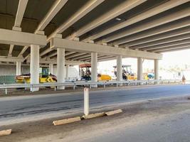 bouw industrieel werk onder de brug en groot snelweg viaduct met de helpen van modern bouw uitrusting zo net zo asfalt rollen foto