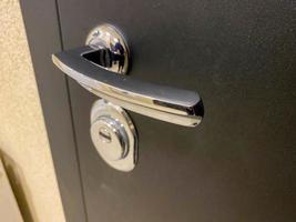 nieuw glimmend chroom metaal deur omgaan met voor een zwart metaal Ingang deur met een sleutelgat in de Ingang gang Bij de Ingang naar de appartement foto