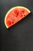 sappig plak van rood watermeloen Aan een steen zwart achtergrond. conceptuele kleuren van zomer. top visie net zo een achtergrond foto