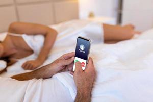 bedrog ontrouw Mens aan het liegen met meesteres in hotel bed. telefoontje van finace naar mobiel telefoon. bedrieger hebben affaire met geheim minnaar en verhouding met een ander vrouw. ontrouw en liefde driehoek. foto