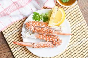 gekookt krabvoedsel op witte plaat en zeevruchtensaus op tafel - krabklauwen schelpdieren foto