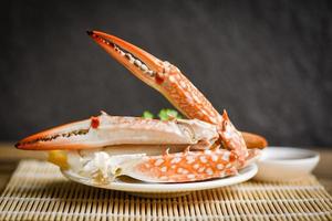 gekookt krabvoedsel op witte plaat en zeevruchtensaus op tafel - krabklauwen schelpdieren foto