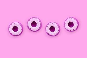 veel klein plastic donuts leugens Aan een pastel kleurrijk achtergrond. vlak leggen minimaal patroon. top visie foto