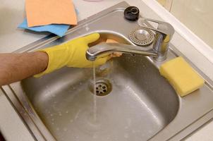 persoon of gezinshoofd schoonmaak de keuken wastafel met spons in dichtbij omhoog visie foto