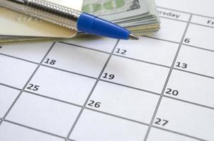 pen en credit kaart Aan veel honderd ons dollar rekeningen Aan kalender bladzijde dichtbij omhoog foto