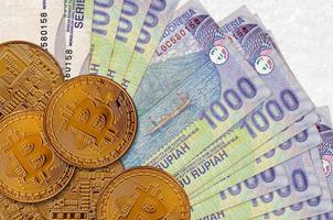 1000 Indonesisch roepia rekeningen en gouden bitcoins. cryptogeld investering concept. crypto mijnbouw of handel foto