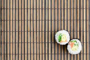 sushi broodjes leugens Aan een bamboe rietje naaien mat. traditioneel Aziatisch voedsel. top visie. vlak leggen minimalisme schot met kopiëren ruimte foto