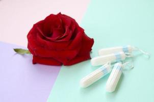 menstruatie- stootkussens en tampons met rood roos bloem Aan veelkleurig achtergrond foto