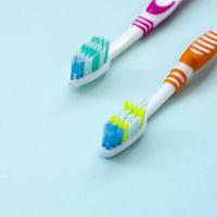 twee tandenborstels liggen Aan een pastel blauw achtergrond. top visie, vlak leggen. minimaal concept foto