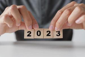 Mens hand- Holding houten kubus blok met 2023 jaar tekst . begin naar jaar 2023. gelukkig nieuw jaren concept. foto