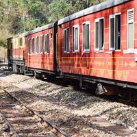 speelgoedtrein die zich op berghellingen beweegt, prachtig uitzicht, een zijberg, een zijvallei die zich op een spoorlijn naar de heuvel beweegt, tussen groen natuurlijk bos. speelgoedtrein van kalka naar shimla in india, indiase trein foto