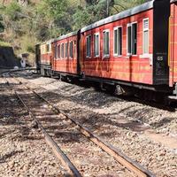 speelgoedtrein die zich op berghellingen beweegt, prachtig uitzicht, een zijberg, een zijvallei die zich op een spoorlijn naar de heuvel beweegt, tussen groen natuurlijk bos. speelgoedtrein van kalka naar shimla in india, indiase trein foto