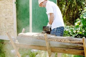 kettingzaag in de handen van een arbeider snijdend brandhout, detailopname foto