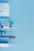 ampul en injectiespuit met de vaccin tegen de virus tegen ziekten Aan een blauw achtergrond. verticaal regeling, verticaal kader foto