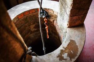 oude steen ronde goed met drinken water en een oranje touw. foto