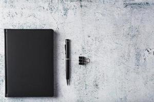 zwart kladblok met een zwart pen Aan een grijs achtergrond foto