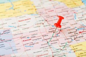 rood klerikaal naald- Aan een kaart van Verenigde Staten van Amerika, Kansas en de hoofdstad topeka. dichtbij omhoog kaart van Kansas met rood tack foto