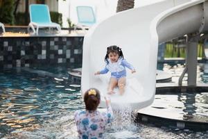 Aziatisch moeder en dochter zwemmen spelen glijbaan zwembad in de zwembad Bij de toevlucht, glimlachen en lachend. hebben pret in de zwembad Bij de toevlucht hotel, familie gelukkig concept. foto